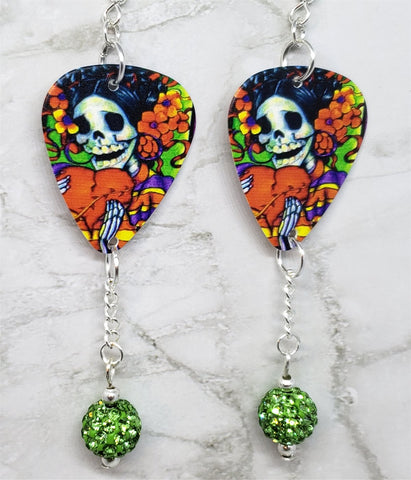 Sugar Skull Surrounded By Flowers Holding a Heart Guitar Pick Earrings with Green Pave Bead Dangles